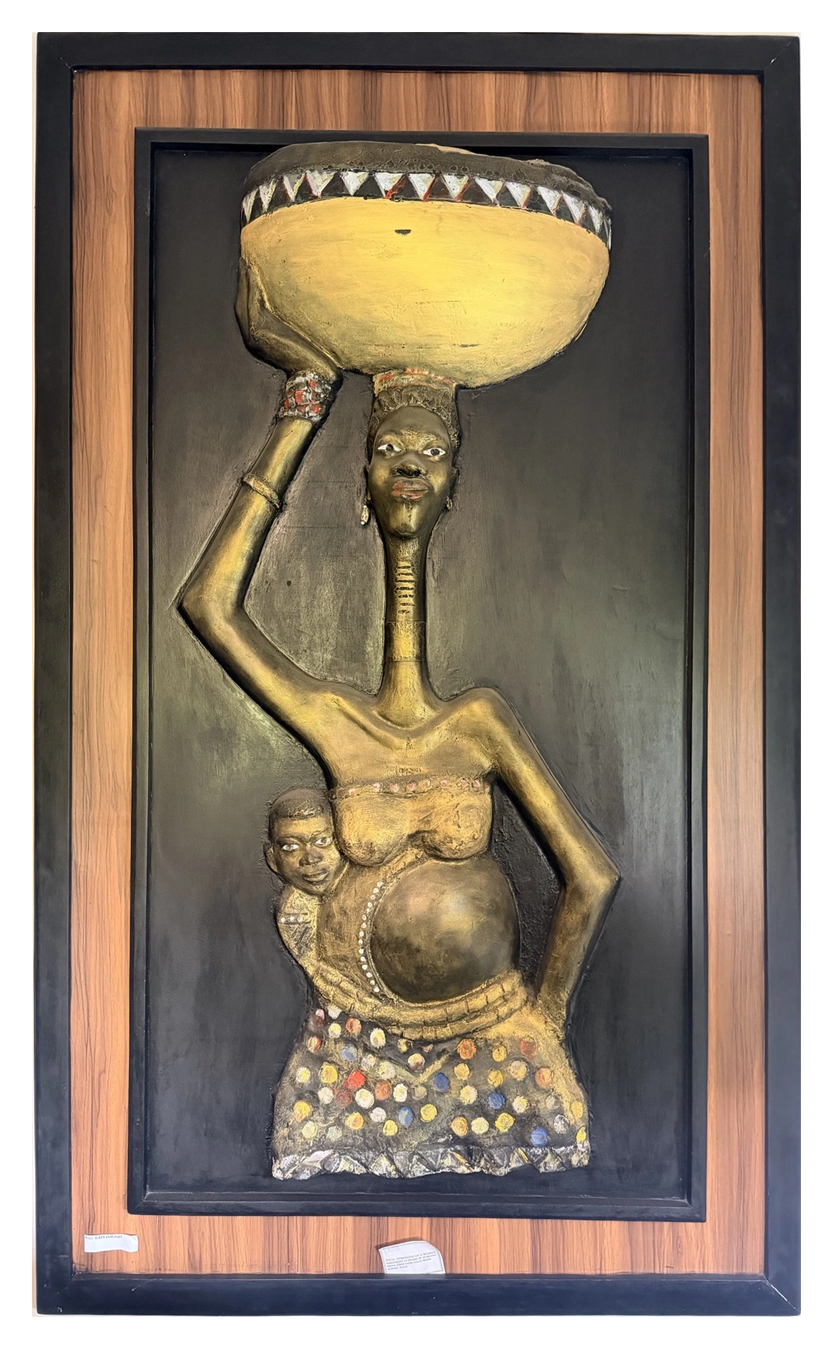 A framed sculptural relief of a figure holding a vessel overhead, with a smaller figure beside her.