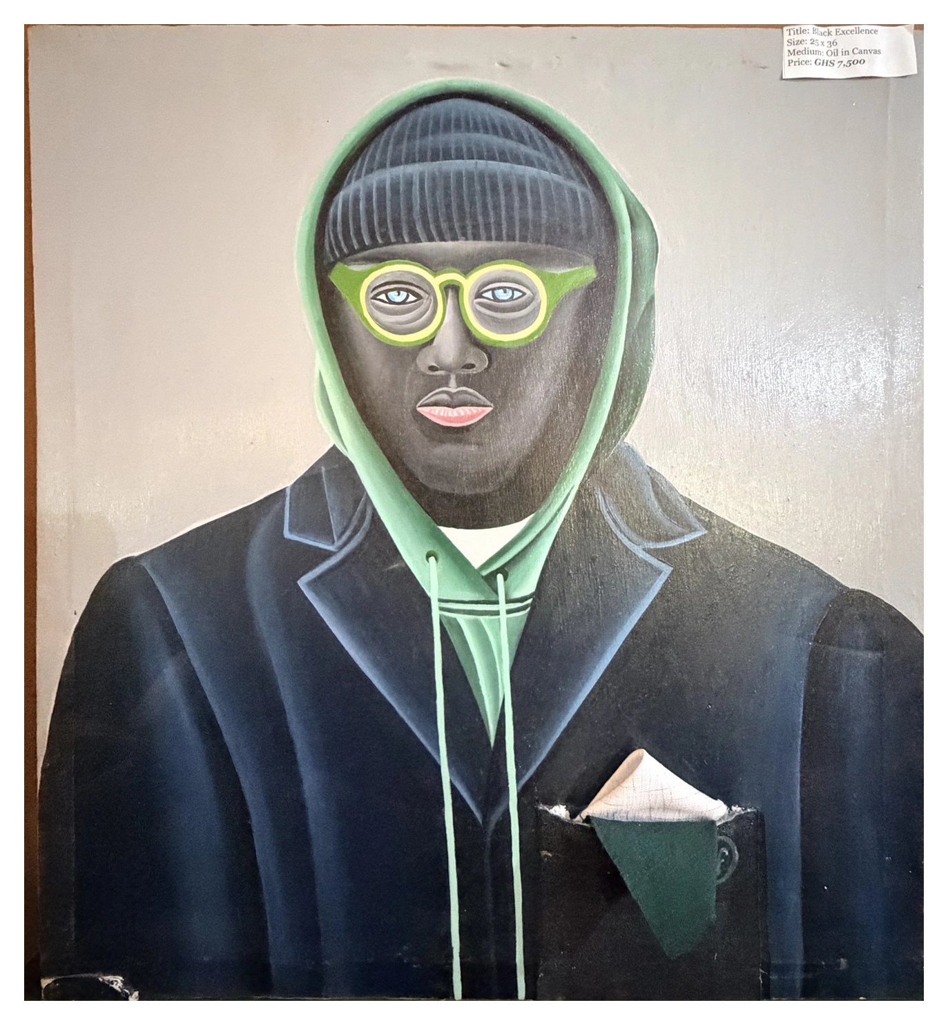 A frontal portrait of a figure in a green hood, round glasses and a dark jacket.